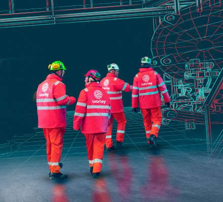 Four Worley people wearing PPE walking together with an overlay of machinery.