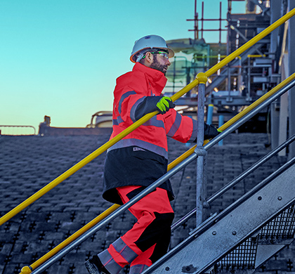 Worley man wearing PPE walking up the stairs on a job site.