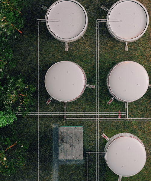 Aerial view of gas tanks next to trees.