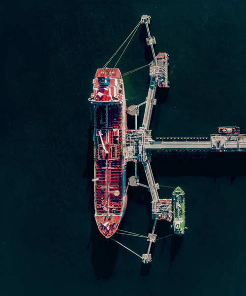 Aerial view of large ship next to an oil storage tanks.