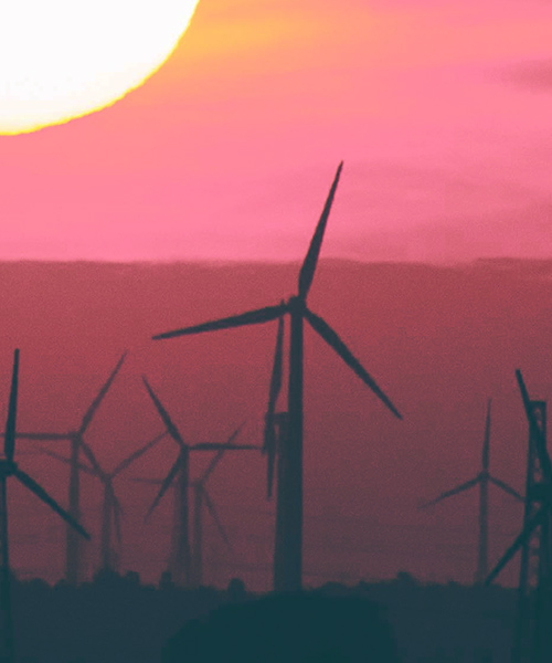 Onshore wind turbines with a large setting sun.