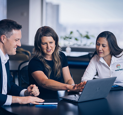 Three Worley people sitting together looking at a laptop screen.