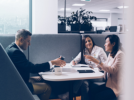 Three Worley people sitting together at a table talking.